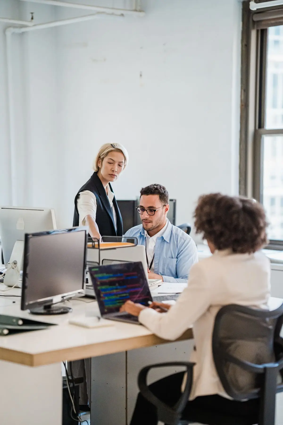 Colleagues collaborating at computer workstations in an office